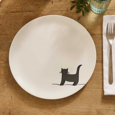 a white plate with a black cat drawn on it next to a fork and knife