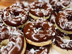 there are many chocolate covered doughnuts on the table together and sprinkled with coconut