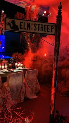 a dining table set up for an event with candles on the tables and red lights in the background