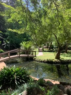 a wooden bridge over a small pond in a park