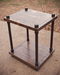 a wooden table sitting on top of a cement ground next to a field and trees