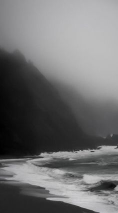 a black and white photo of the ocean on a foggy day