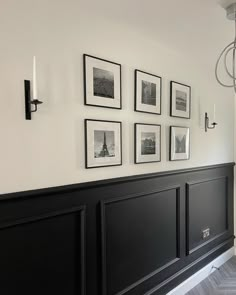 a black headboard with pictures on the wall above it and a chandelier