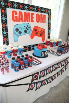 a table topped with cakes and cupcakes next to a game on sign that says,