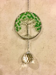 a metal tree with green beads hanging from it's side on a white wall