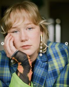 a woman with blonde hair wearing a blue jacket and green shirt is looking at the camera