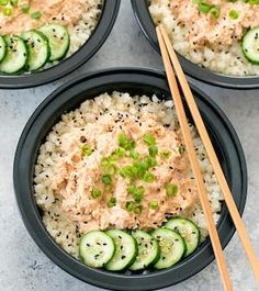 three black bowls filled with rice, cucumbers and salmon on top of each other