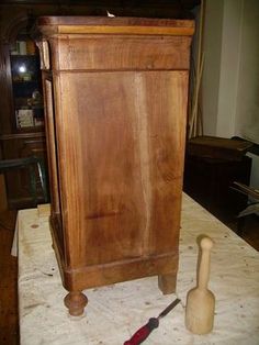 an old wooden cabinet sitting on top of a table next to a knife and brush