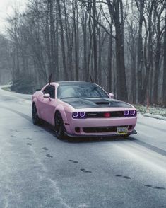 a pink and black car parked on the side of a road next to some trees