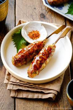 two chicken skewers on a plate with sauce