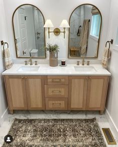 a bathroom with two sinks, mirrors and rugs on the floor in front of them