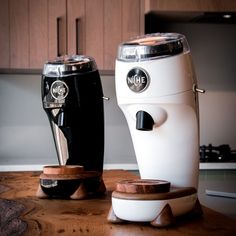 two coffee machines sitting on top of a wooden table