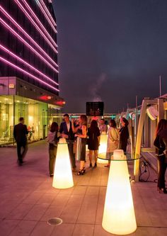 people are standing on the roof of a building at night with their lights turned on