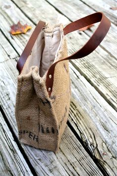 an old burlocked bag sitting on top of a wooden table next to a leaf