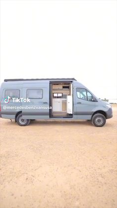 a blue van parked on top of a dirt field