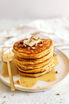 a stack of pancakes on a plate with butter and syrup drizzled over them