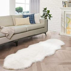 a living room filled with furniture and a white sheepskin rug on top of a hard wood floor