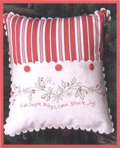 a red and white pillow sitting on top of a christmas tree with the words home is where we came from joy