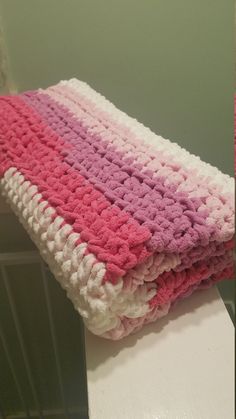 a pink and white crocheted blanket sitting on top of a table