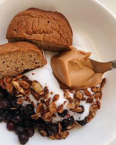 a white plate topped with granola, raisins and sliced loaf of bread