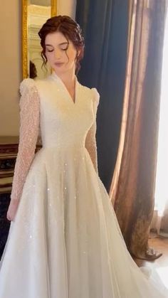 a woman in a white wedding dress standing next to a mirror