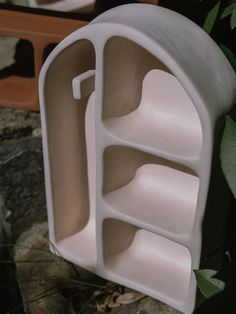 a white plastic object with three compartments on the front and two shelves in the back