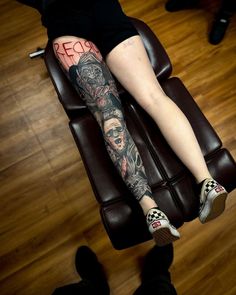 a woman with tattoos on her leg sitting in a chair