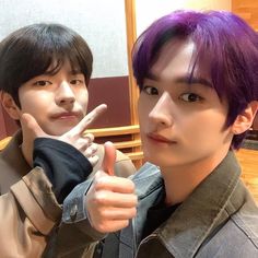 two young men with purple hair giving the peace sign while standing next to each other