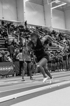 a woman is running on a track with a tennis racket in her hand as people watch from the bleachers