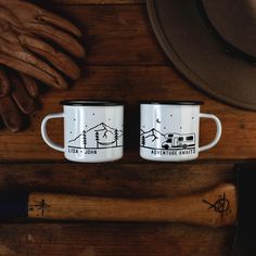 two coffee mugs sitting on top of a wooden table next to a baseball bat