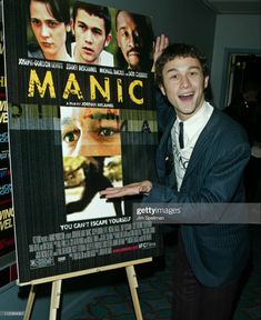 a man in a suit and tie standing next to a poster for the movie manic