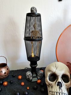 a skull sitting on top of a table next to a lamp and some pumpkins