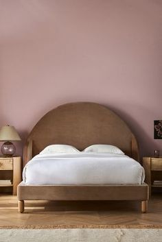 a large bed sitting next to two nightstands on either side of a pink wall