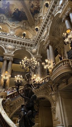 an ornate staircase with chandeliers and paintings on the ceiling in a large building