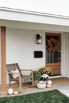 the front porch is decorated for fall with pumpkins and mumlocks on the lawn