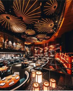 the interior of a restaurant with many tables and chairs, lit up by lights from above