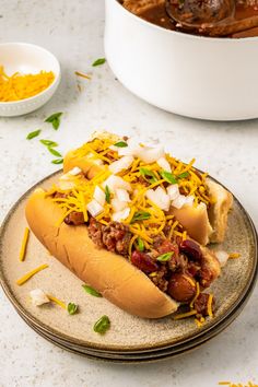 a chili dog with cheese and onions on a plate