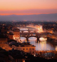 the city is lit up at night with lights on and bridges crossing over it's water