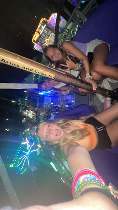 three girls are posing for the camera in front of a stage with lights and fireworks