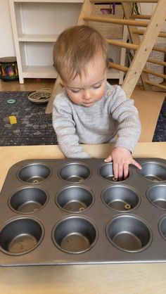 a toddler reaching into a muffin pan