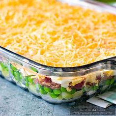 a casserole dish with green beans, cheese and bacon in it on a table