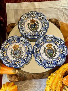 three blue and white plates sitting on top of a table next to some pumpkins