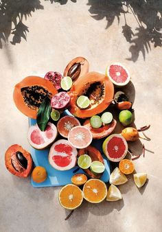 an overhead view of various fruits and vegetables on a blue plate with shadow from above