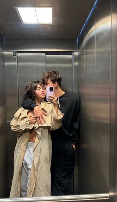 a man and woman taking a selfie in an elevator