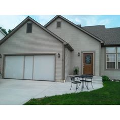 a house that has a table and chairs in front of it with the garage door open