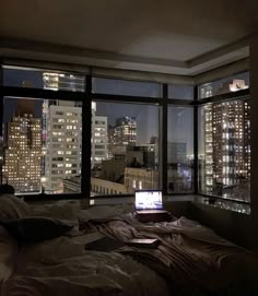 a laptop computer sitting on top of a bed in front of a window at night