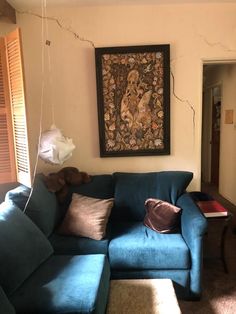 a living room with blue couches and a painting on the wall above it's head