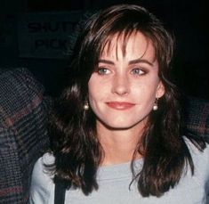 a woman sitting in a chair with her eyes closed and smiling at the camera while wearing a sweater