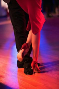 two people in red and black shoes on a dance floor with their feet touching each other