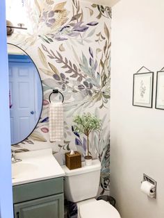 a bathroom with a toilet, sink and wallpapered walls in different colors on the walls